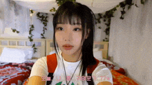 a girl laying on a bed with korean writing on the bottom of her shirt
