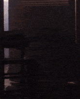 a silhouette of a person standing in a dark room with a stack of books on a table
