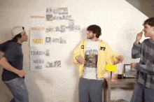 three men are standing in front of a wall with a poster that says incredible