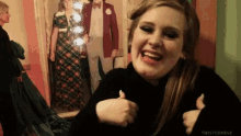 a woman is giving a thumbs up in front of a picture of a man and woman