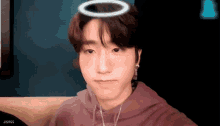 a young man with a halo on his head is sitting on a couch taking a selfie .