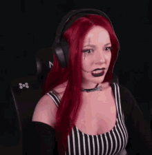 a woman with red hair and headphones is sitting in a chair with her hands outstretched .