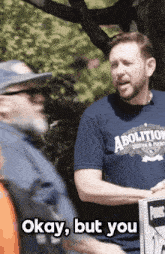 a man wearing a blue shirt that says abolition is holding a sign that says okay but you