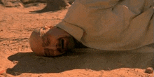 a man is laying on the ground in the sand with his eyes closed and his mouth open .