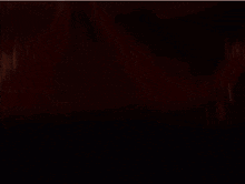 a girl with long red hair is standing in a dark room