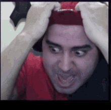 a man wearing a red hat and a red shirt is making a funny face .
