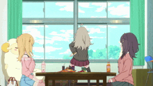 three girls are sitting at a table with a bottle of orange juice on it