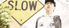 a young man is standing in front of a yellow sign that says slow .