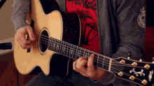 a man playing an acoustic guitar with a shirt that says ' hawaii ' on it