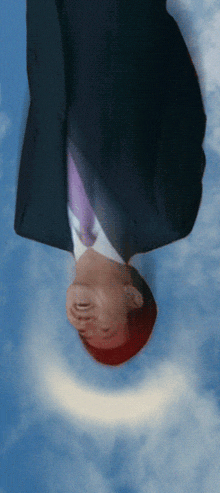 a man in a suit and tie is upside down against a blue sky