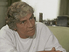a man with gray hair is wearing a white sweater