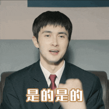 a man in a suit and tie is pointing at the camera with chinese writing above him