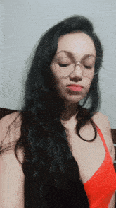 a woman wearing glasses and a red bra is looking down