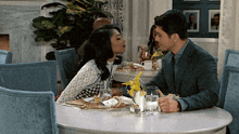 a man and a woman are sitting at a table kissing