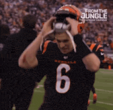 a football player with the number 6 on his jersey is putting on his helmet