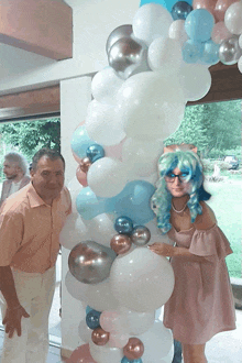 a man and a woman are standing in front of a balloon display