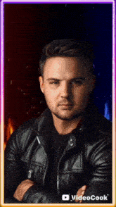 a man in a black leather jacket stands with his arms crossed