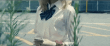 a woman in a white shirt and blue tie is looking at her phone