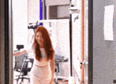 a woman with red hair is standing in a doorway in a room .
