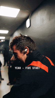 a man in a black and red jacket says " yeah five star "