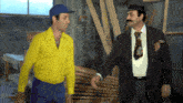 a man in a yellow shirt and a man in a black suit are standing next to each other