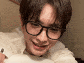 a young man wearing glasses and a white shirt smiles for the camera