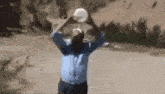 a man in a blue shirt is pouring a bucket of water on his head