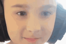 a close up of a child 's face wearing headphones and making a funny face .