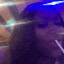 a woman smoking a cigarette in a dark room with a blue light behind her