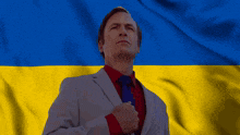 a man in a suit and tie stands in front of a flag