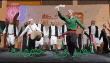 a group of people are dancing in front of a sign that says ' arabic '