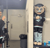 a man standing next to a mascot wearing a shirt that says ' seattle ' on it