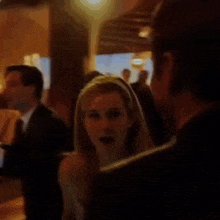 a man in a suit and tie is talking to a woman in a blue dress .