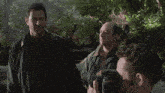 three men are standing in a forest and one of them says " yeah "
