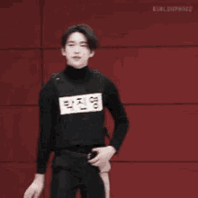 a group of young men are standing next to each other in front of a red wall and dancing .
