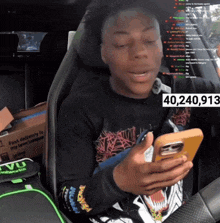 a man sitting in a car looking at a cell phone with the number 40240,913 on the bottom right