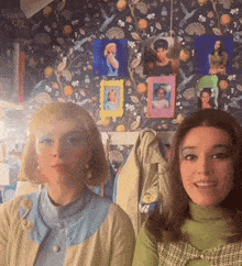 two women are posing for a picture in front of a wall with pictures and a sign that says " winner "
