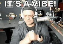 a man wearing headphones in front of a microphone with the words it 's a vibe behind him