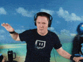 a man wearing headphones and a black t-shirt with a twitch logo on it .