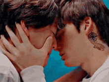 a man with a compass tattoo on his neck is kissing another man .