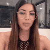 a woman wearing glasses and a polka dot shirt looks at the camera