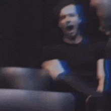 a blurry picture of a man in a black shirt in a dark room .