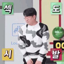 a man in a cow print sweater is standing in front of a green balloon with korean writing on it