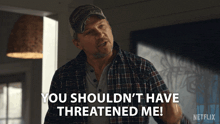 a man in a plaid shirt is saying " you shouldn 't have threatened me "