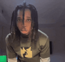 a man with dreadlocks is wearing a t-shirt with a picture of a man 's face on it