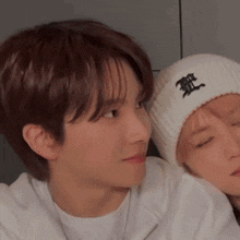 a man and a woman are sitting next to each other and the man is wearing a beanie with chinese characters on it .