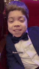 a young boy wearing a suit and bow tie is sitting in a chair .