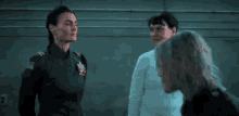 a group of women are standing next to each other in a dark room talking to each other .