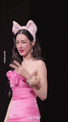 a woman wearing a pink dress and bunny ears waves