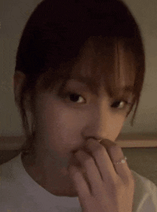 a woman is covering her mouth with her hand while wearing a ring .